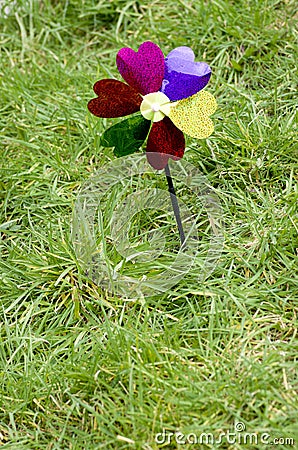 Toy windmill flower on green grass background,concept of green energy. Stock Photo