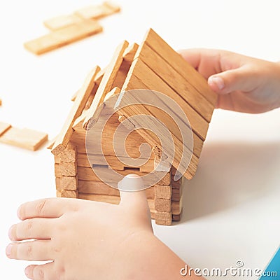 Toy wooden house. Child builds small house. Dream about home. Small model of house from wooden blocks Stock Photo