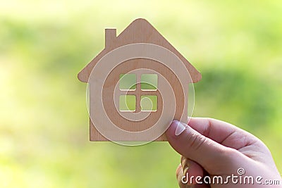 Toy wooden house in hand on a light green background, Concept - buying a house on credit or mortgage, safe and affordable housing Stock Photo