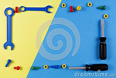 Toys background. Kids construction toys tools frame on blue and yellow background. Top view Stock Photo