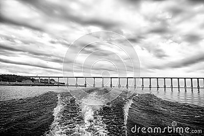 Trace of speed boat on blue sea water in manaus, brazil. Seascape with bridge on horizon on cloudy sky. travelling and Stock Photo