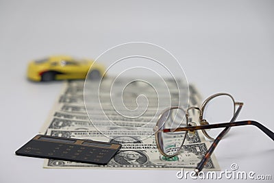 Track of dollar bills. Toy car on a white background with glasses and a calculator, the concept of car ownership cost Stock Photo