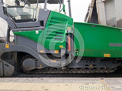 Tracked paver. Industrial pavement truck laying fresh asphalt on construction site. Asphalt a new on the road texture and a Stock Photo