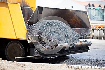 Tracked paver laying fresh asphalt pavement during road constru Stock Photo