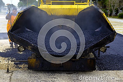 Tracked paver laying fresh asphalt pavement Stock Photo