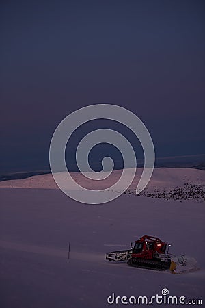 Tractor cleaning snow on the ski slopes in the Alps Editorial Stock Photo