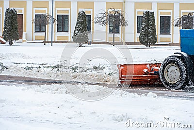 A tractor cleans snow in the city in winter after a snowfall. Cleaning city streets from snow. Tractor driver at work in the city Editorial Stock Photo