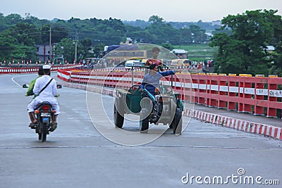 Sunamganj, Bangaldesh- October 11,2016: A tractor driver is driving over bridge and pointing at something Editorial Stock Photo