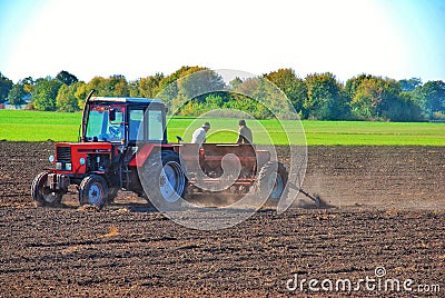 tractor drivers plow a field with a tractor. people work on a tractor seeder. Editorial Stock Photo