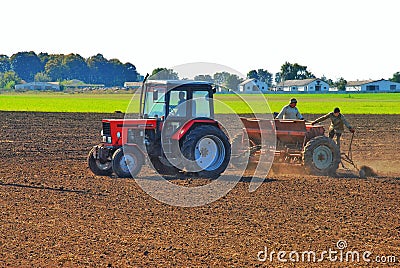 tractor drivers plow a field with a tractor. people work on a tractor seeder. Editorial Stock Photo