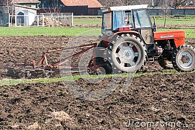 Tractor equipped with harrow working on the field Editorial Stock Photo