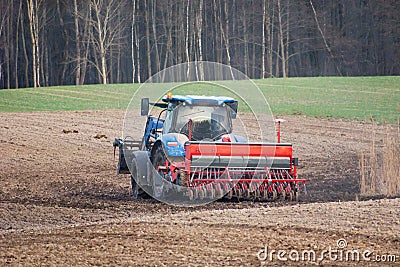 Tractor with a grain seeder in the field Stock Photo