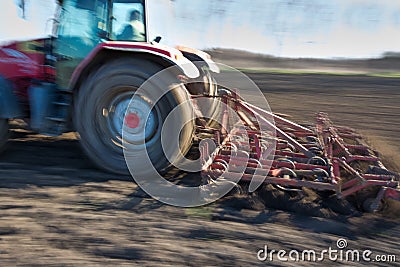 Tractor harrowing land in springtime Stock Photo