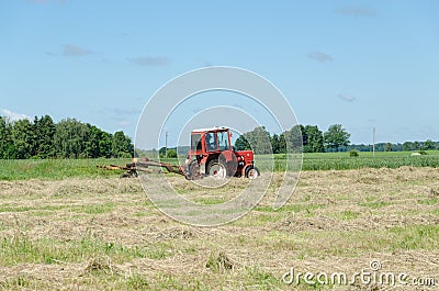 Tractor machine equipment ted dry grass in field Stock Photo