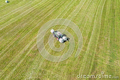 Tractor makes hay bales on a field Stock Photo