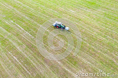Tractor makes hay bales on a field Stock Photo