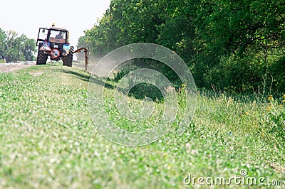 Tractors machines mowing lawn grass along road Stock Photo