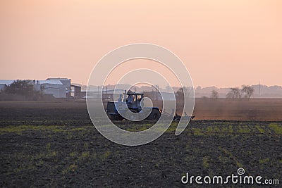 Tractor plowing plow the field on a background sunset Stock Photo