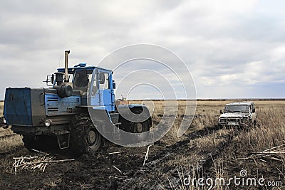 Tractor pulls a stuck car out of the fields Stock Photo