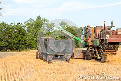 Tractor pulls up for loading to the combine with wheat Editorial Stock Photo