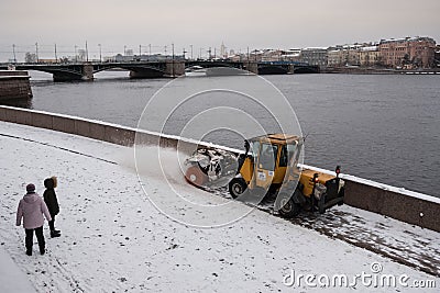 Tractor removes snow from the sidewalk Editorial Stock Photo