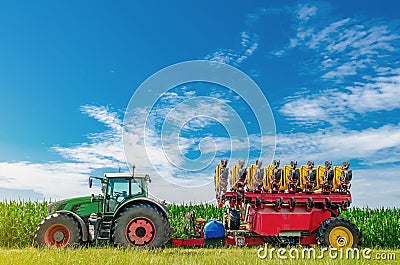 Tractor seeder in a green corn field. Bright summer agricultural view with machinery Stock Photo