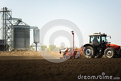 Tractor and seeder for sowing cornin. Silo in background Stock Photo