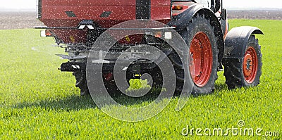 Tractor spreading artificial fertilizers in field Stock Photo