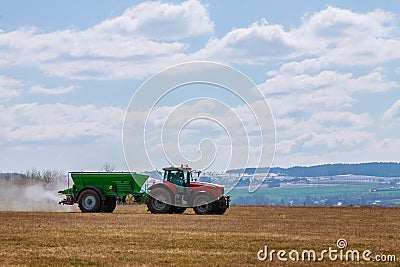 Tractor spreading fertilizer on grass field. Agricultural work Stock Photo