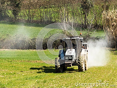 Tractor working spreading fertiliser Stock Photo