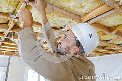 Tradesman using screwdriver on ceiling timbers Stock Photo