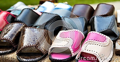 Trading in the market of shoes with flip flops made of genuine leather. Multicolour woven leather sandals, comfortable Stock Photo