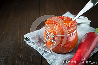 Traditional adjika hot chili pepper sauce paste harissa on wooden board. Tunisia, georgian and arabic cuisine. Horizontal Stock Photo