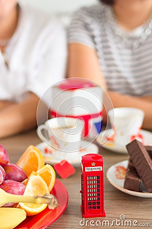 Traditional afternoon tea of british ceremony with such symbol of britishness as toy telephone box Stock Photo