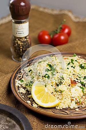 Traditional Arabic salad or Tabbouleh on ceramic plate, healthy vegetarian dish with couscous, tomatoes, parsley, mint Stock Photo