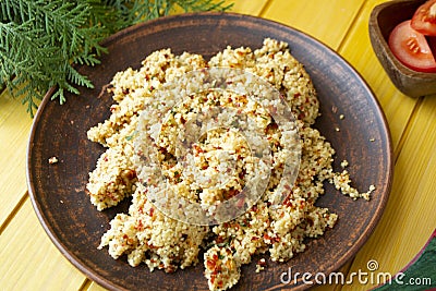 Traditional arabic salad tabbouleh with couscous, vegetables and herbs on yellow wooden background. Stock Photo