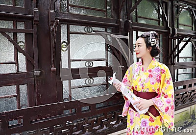 Traditional Asian Japanese woman bride Geisha wearing kimono play in a graden hold an umbrella stand by a boat Stock Photo