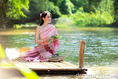 Traditional asian woman Thai dress sitting and relax in wood bridge nature river. Stock Photo