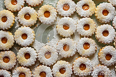 Traditional Austrian home baked Christmas cookies Linzer eyes with apricot jam powdered on baking tray. Process of preparation Stock Photo