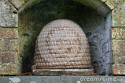 A traditional bee skep in a wall alcove Stock Photo