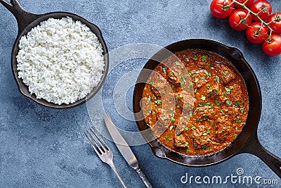 Traditional Beef Madras Indian spicy lamb food with rice and tomatoes in cast iron pan Stock Photo