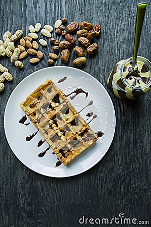 Traditional Belgian waffles covered in chocolate on a dark wooden background. Tasty breakfast . Decorated with raschlichnymi nuts Stock Photo