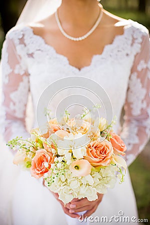 Traditional bride with beautiful orange, pink, and white wedding bouquet of flowers Stock Photo