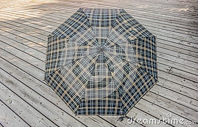 Traditional checkered umbrella on a wooden deck outside Stock Photo