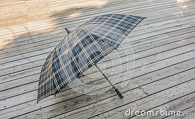 Traditional checkered umbrella on a wooden deck outside Stock Photo