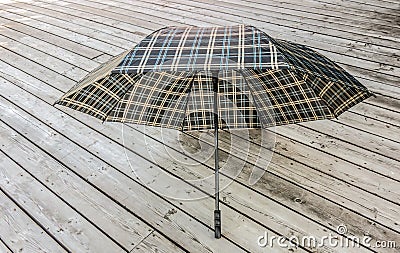 Traditional checkered umbrella on a wooden deck outside Stock Photo