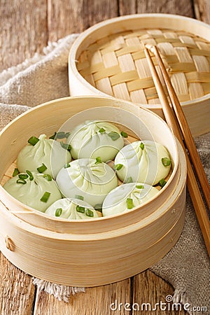 Traditional chinese baozi steam buns in a bamboo steamer basket close-up. Vertical Stock Photo