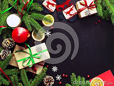 Traditional Christmas dark background top view. New Year composition Spruce branch Pine cone Presents Orange Snowflakes Stock Photo