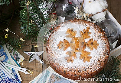 Traditional Christmas fruitcake on the background of a box with Christmas toys and fir branches. Stock Photo