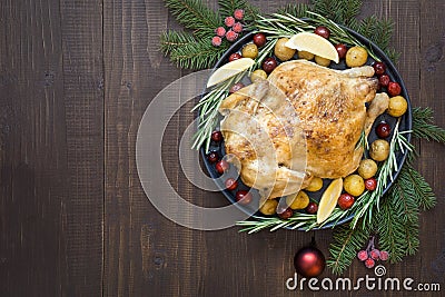 Traditional Christmas roasted chicken with potatoes and rosemary on wooden table. Top view. Stock Photo